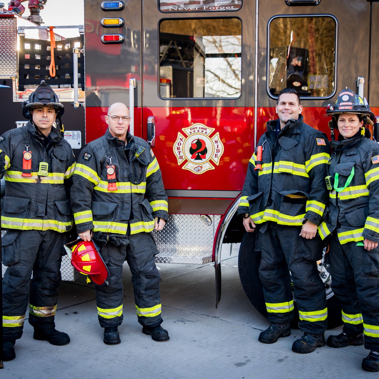 Michigan City firefighters standing in full turnout gear next to a fire engine from the North Side station